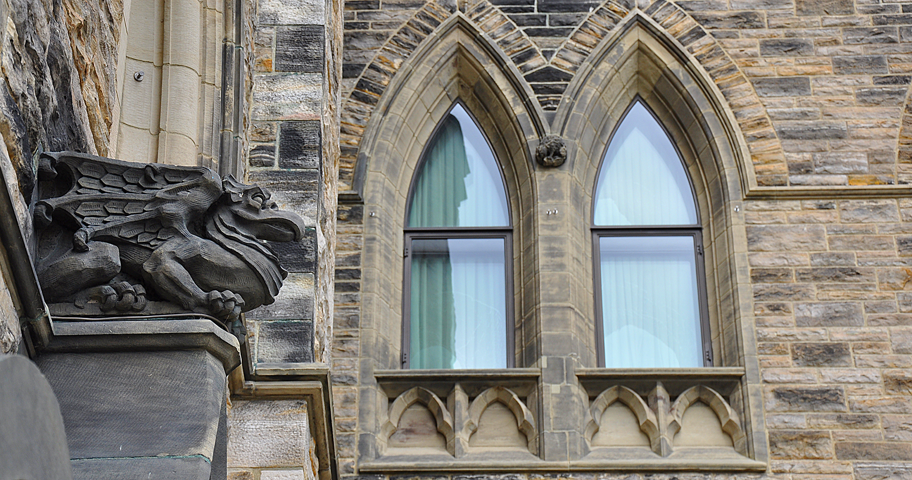 Sculpté en pierre, un griffon s’accroupit au sommet d’une colonne de l’édifice du Centre sur la Colline du Parlement.