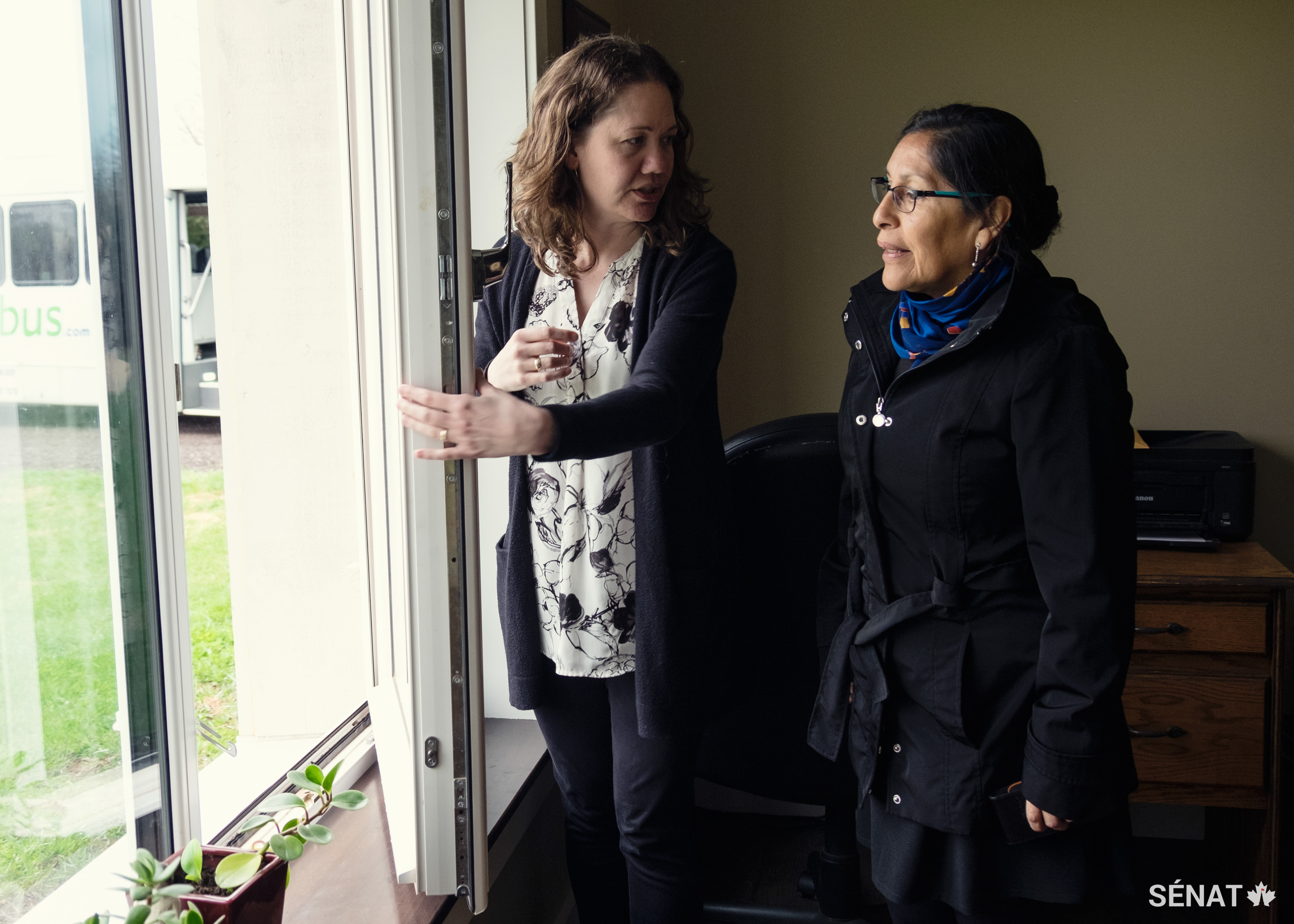 Beth Peters (à gauche), propriétaire d’une maison passive, montre les fenêtres éconergétiques de sa maison à la sénatrice Galvez.
