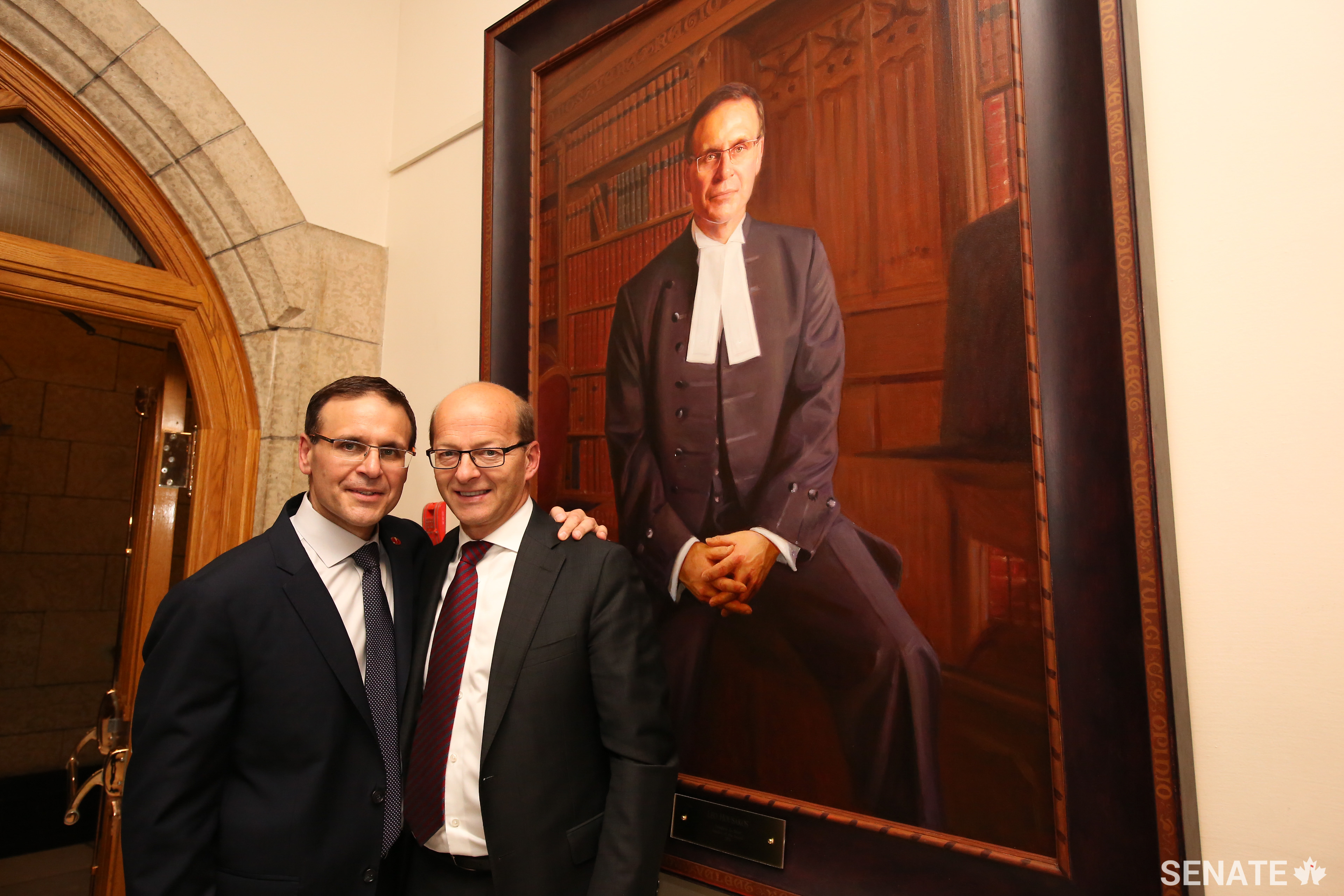 Senator Leo Housakos, left, shares a moment with friend and colleague Senator Claude Carignan after a portrait commemorating Senator Housakos’ time as Speaker was hung in Parliament.