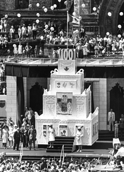 La reine Elizabeth II coupe un gâteau d’anniversaire de neuf mètres lors des célébrations du centenaire du Canada sur la Colline du Parlement en 1967. (Bibliothèque et Archives Canada)