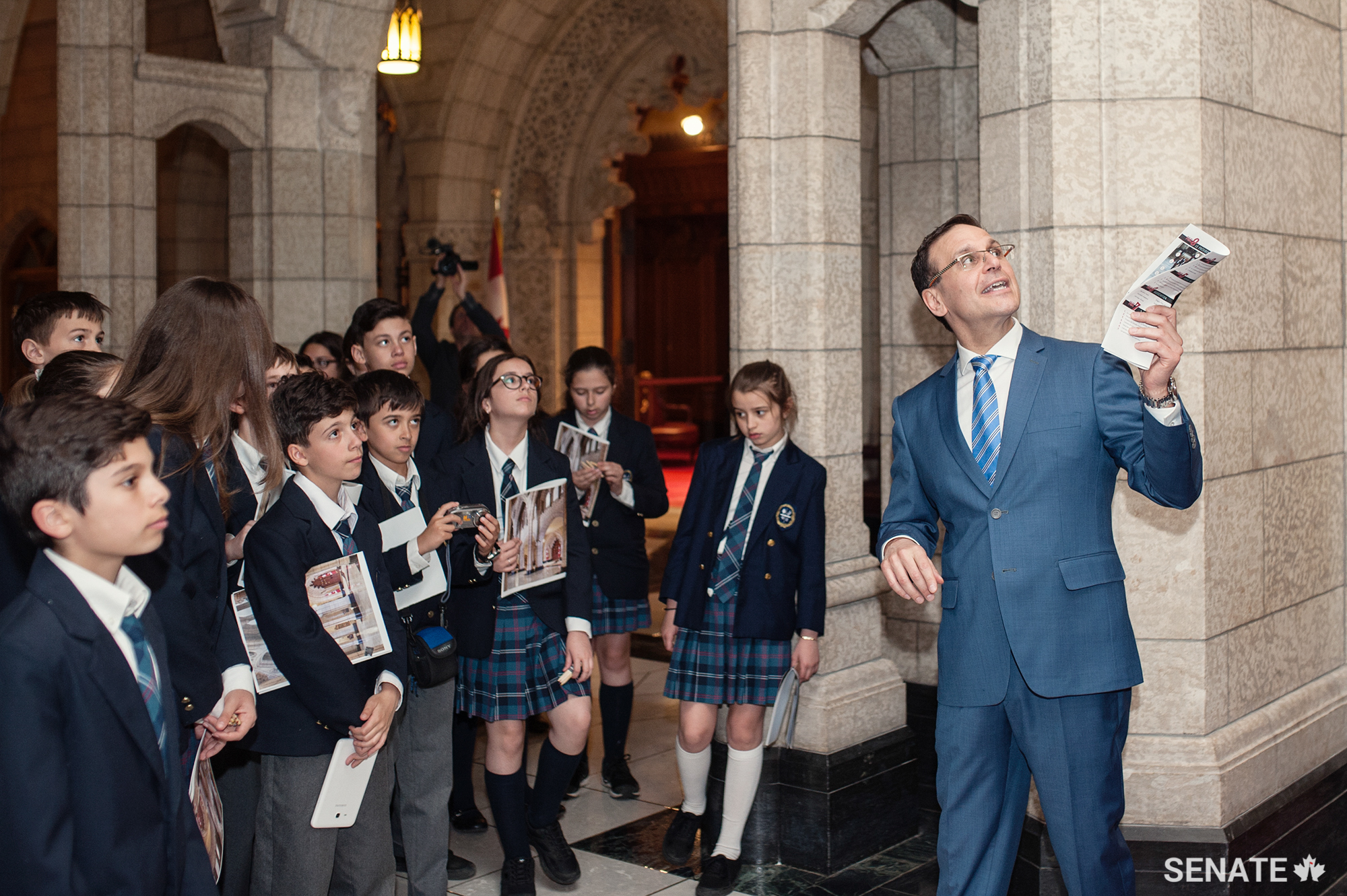 Pointing out the portrait of the King George VI, who overcame a stammer to lead the Commonwealth during the Second World War, Senator Housakos reminds students that they can do anything they put their minds to.