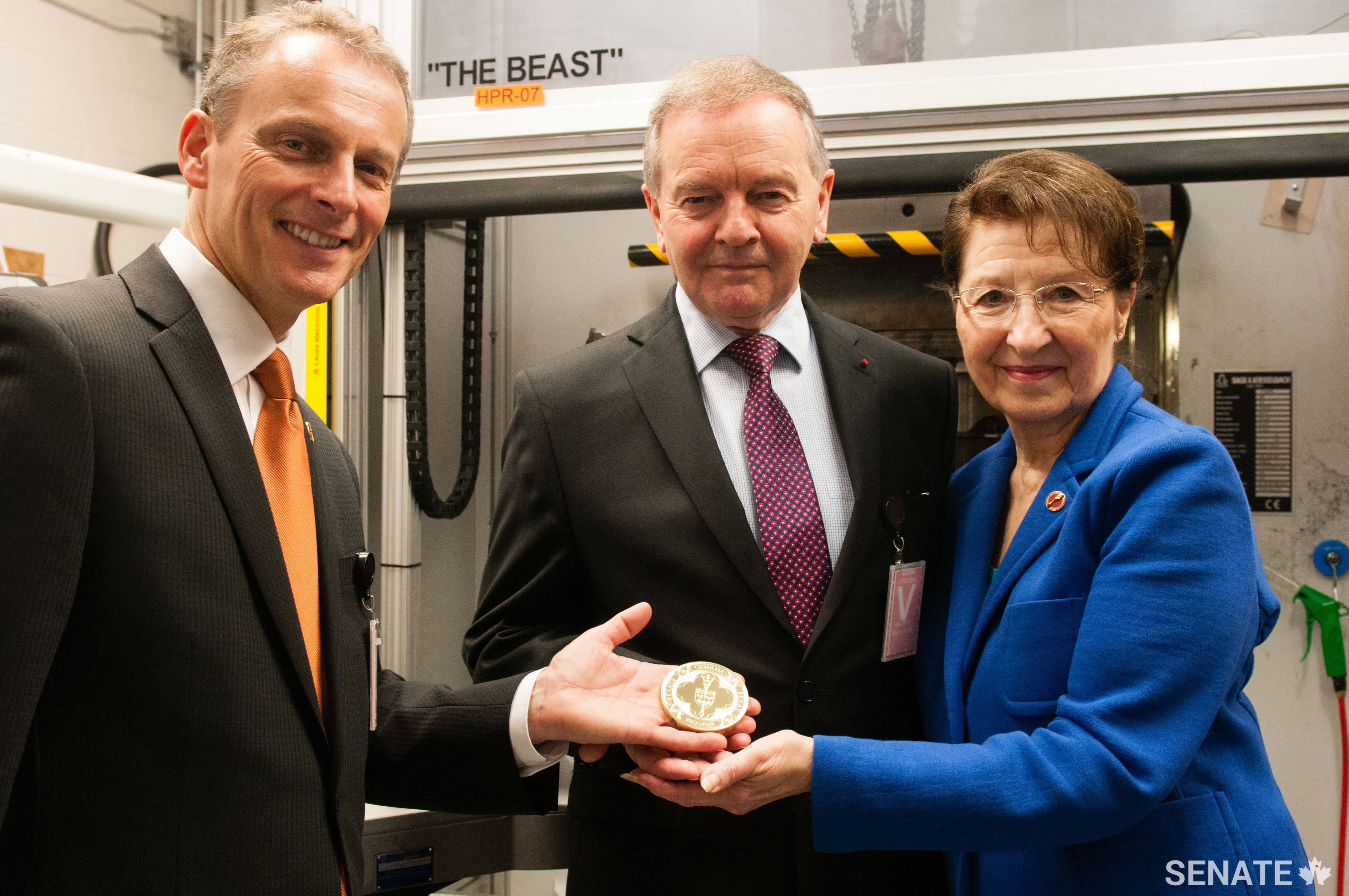 Senators David Wells, Serge Joyal and Betty Unger hold up the first test Senate of Canada Sesquicentennial Medal at the Royal Canadian Mint on June 7, 2017.