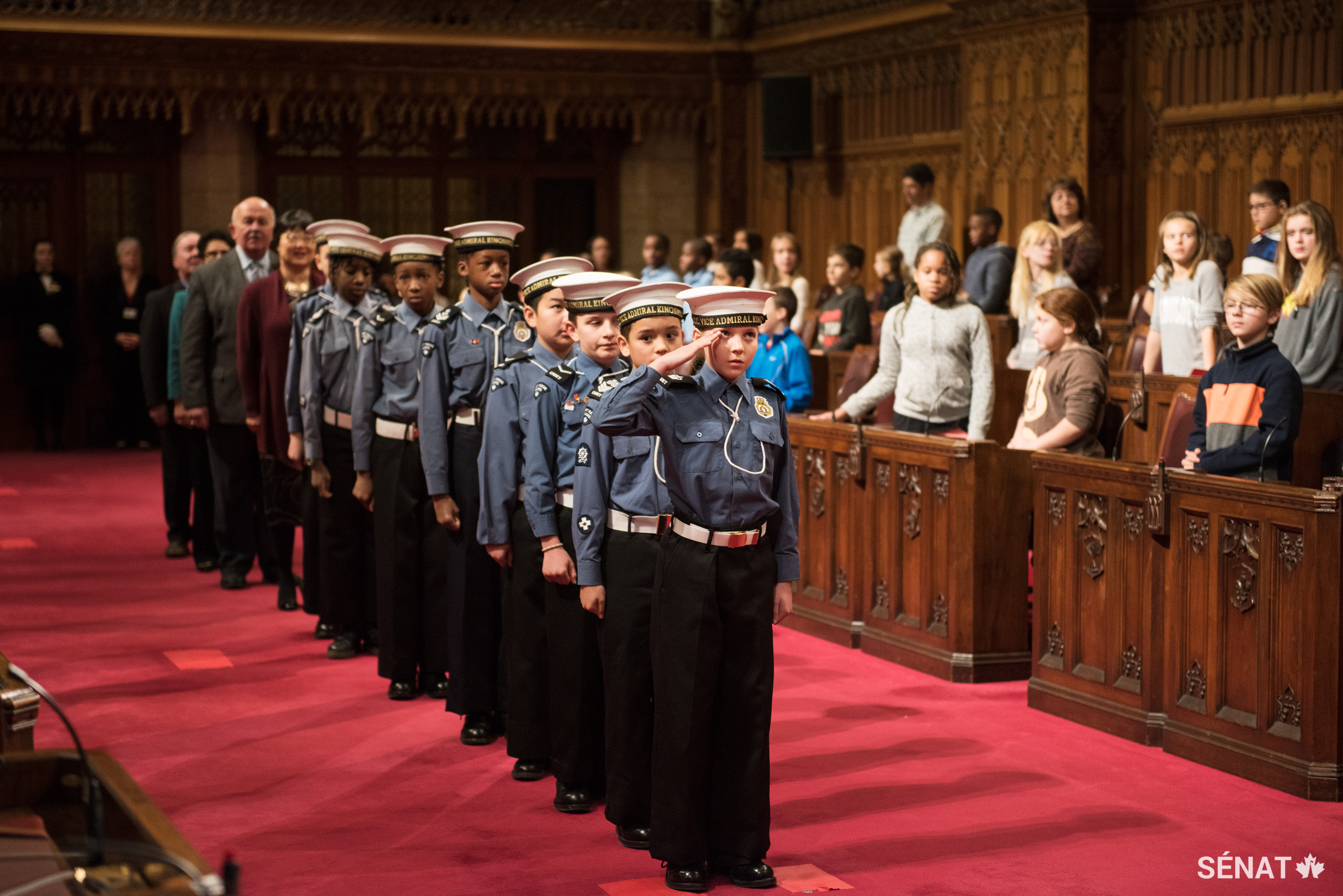 Des cadets de la Ligue navale du Canada conduisent les sénateurs dans la Chambre rouge pour lancer la célébration de la Journée nationale de l’enfant.