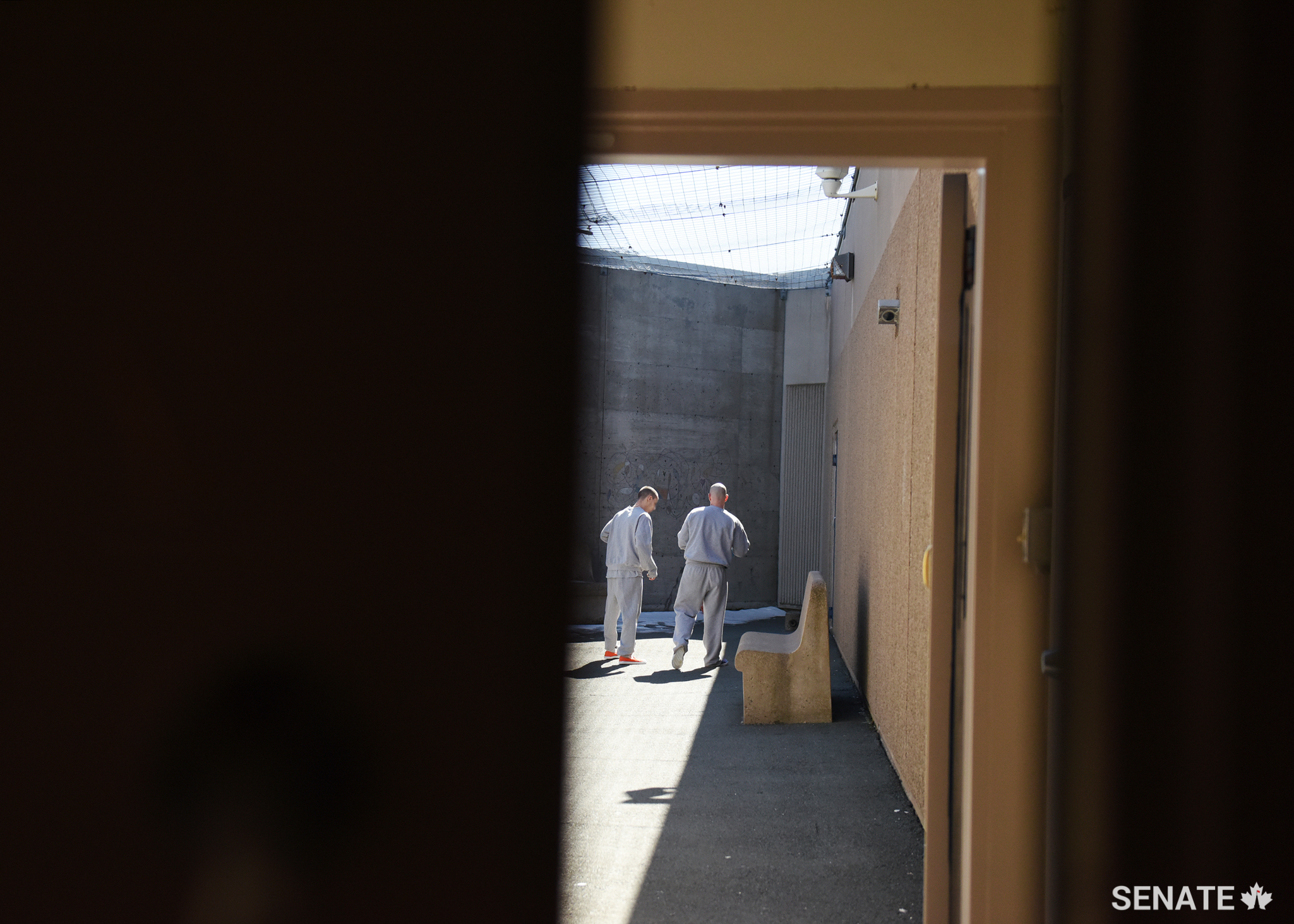 Two residents at the East Coast Forensic Hospital get what exercise they can as sunlight filters through the wire that prevents contraband from being thrown into the facility from the outside world. As this is a hospital and a correctional facility, security is tight — most patients in this facility have come into conflict with the law as a result of mental health issues.