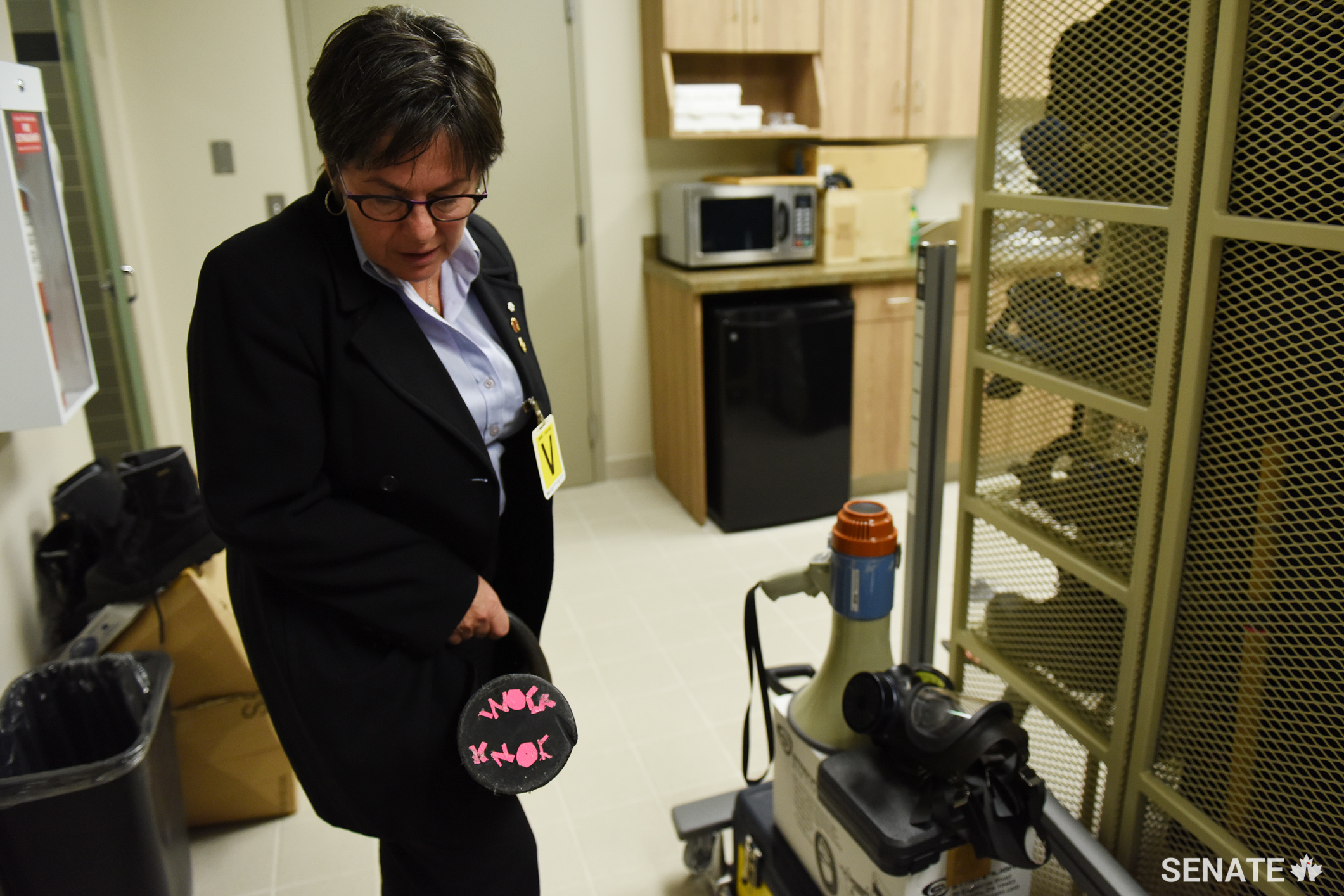 Senator Kim Pate examines a battering ram in the prison armoury. The end has the words “knock knock” written on it in pink tape.