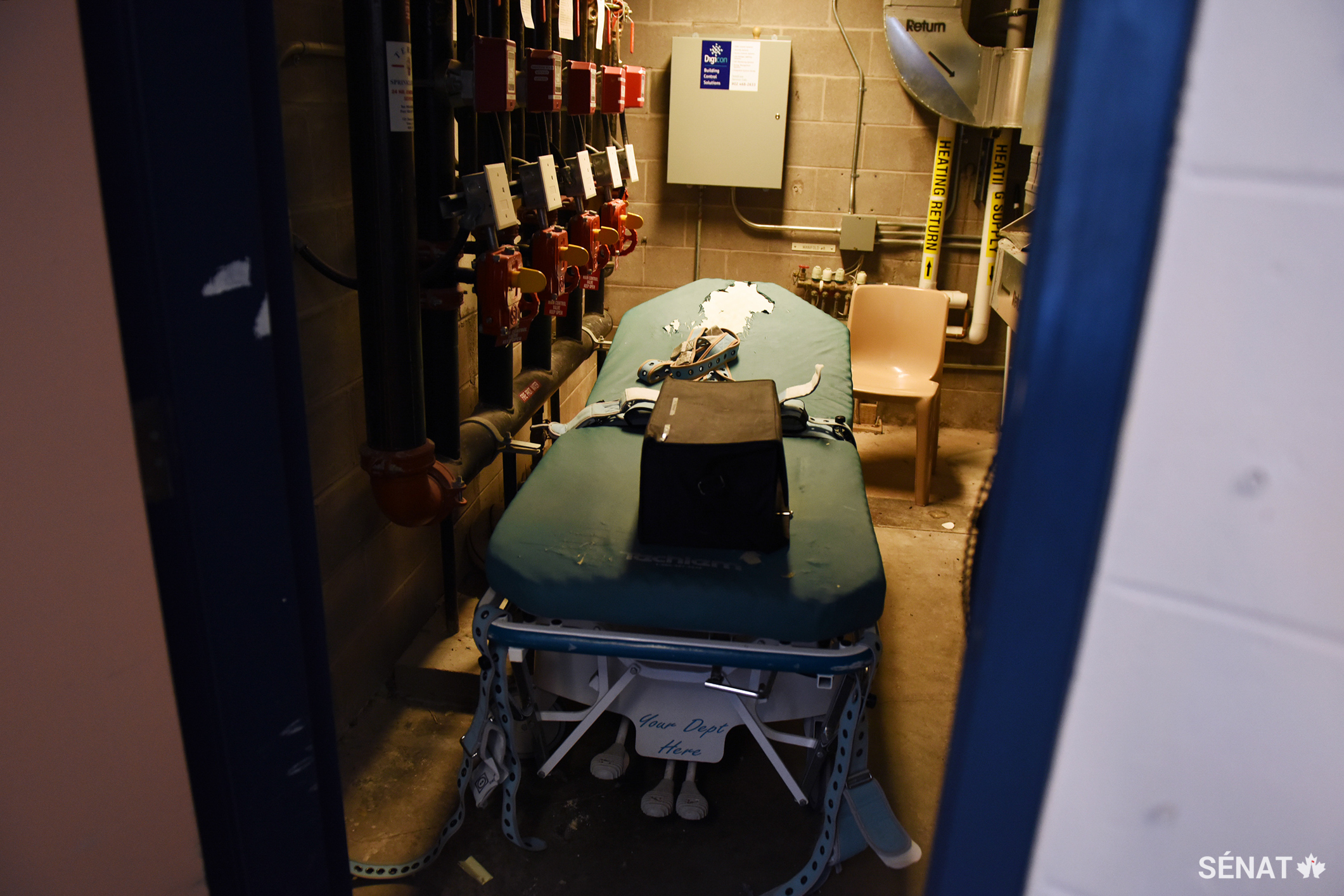 Un lit de contention se trouve dans une salle de rangement. Il est équipé de sangles et utilisé principalement pour les prisonnières qui se mutilent.