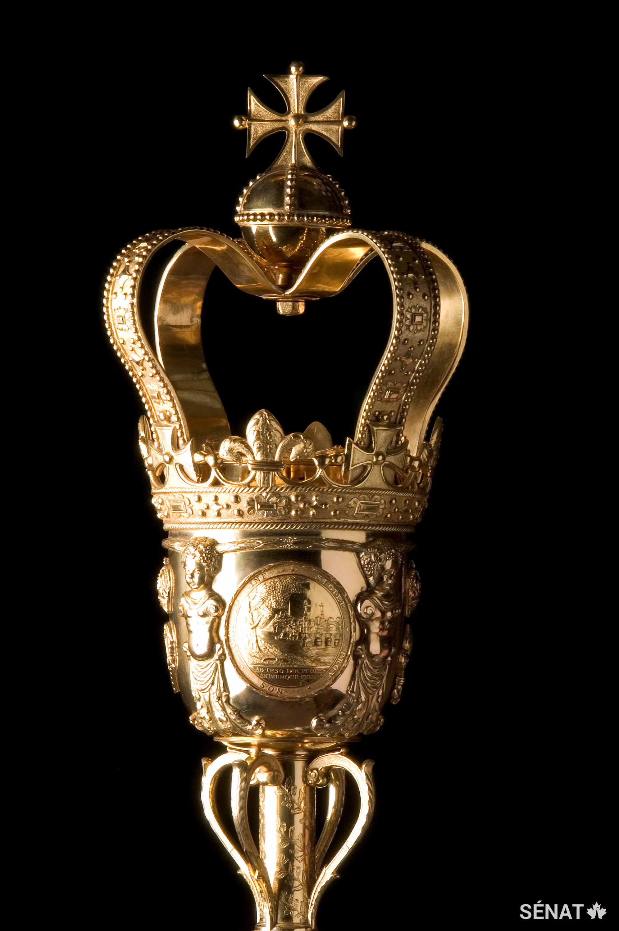 La masse du Sénat de 1,6 m faite de laiton plaqué d’or pèse environ 11 kg et est le symbole de l’autorité du monarque au sein du Sénat du Canada.