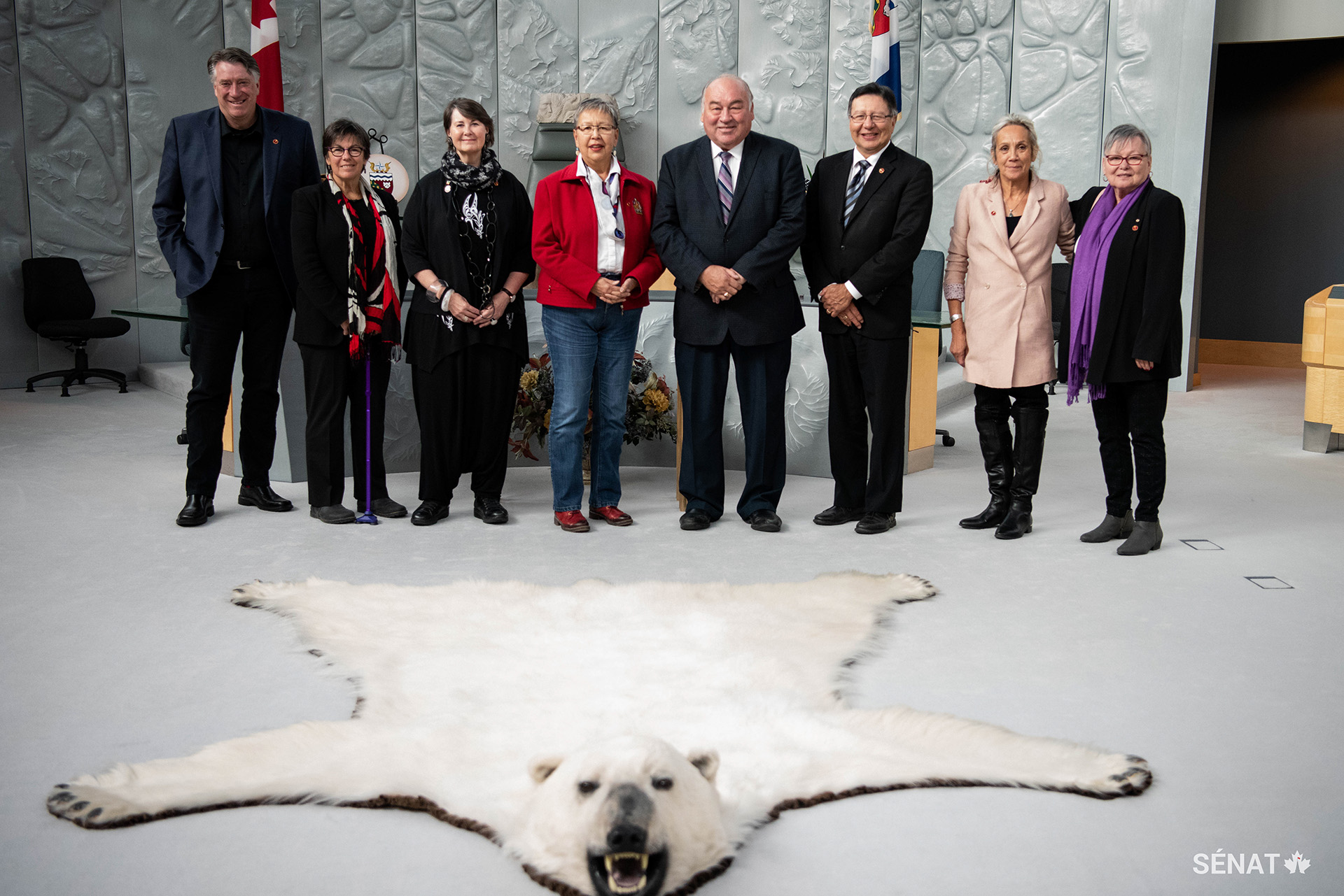 Des membres du Comité sénatorial des peuples autochtones en compagnie du premier ministre des Territoires du Nord Ouest, Bob McLeod, dans la chambre de l’Assemblée législative, à Yellowknife. Le premier ministre a salué le travail du comité dans sa mission d’étude.