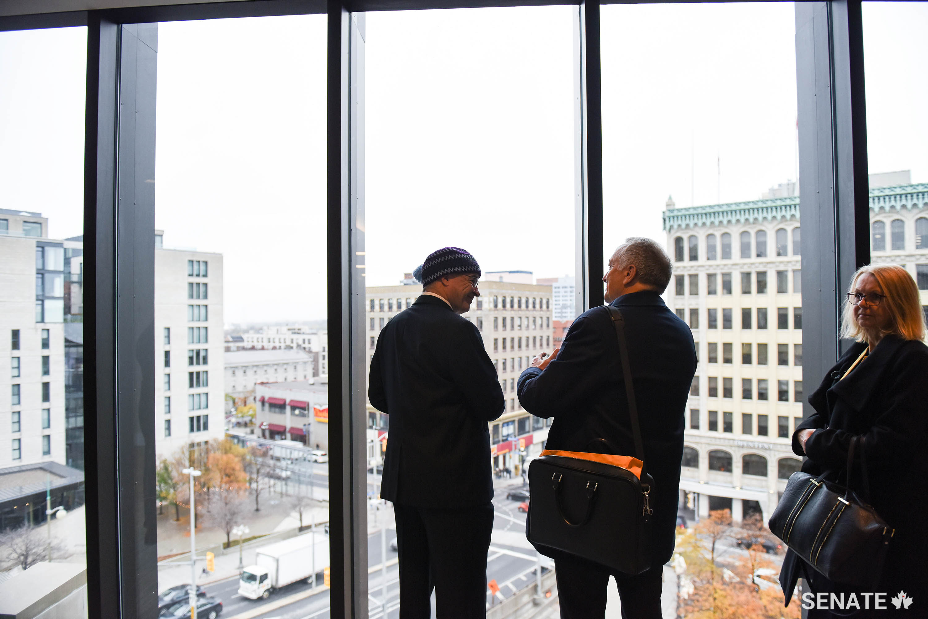 Senators Patterson and Massicotte take in views of the intersection of Rideau Street and Sussex Drive through windows designed to keep drafts out and treated air in, optimizing the Senate of Canada Building’s heating and cooling system.