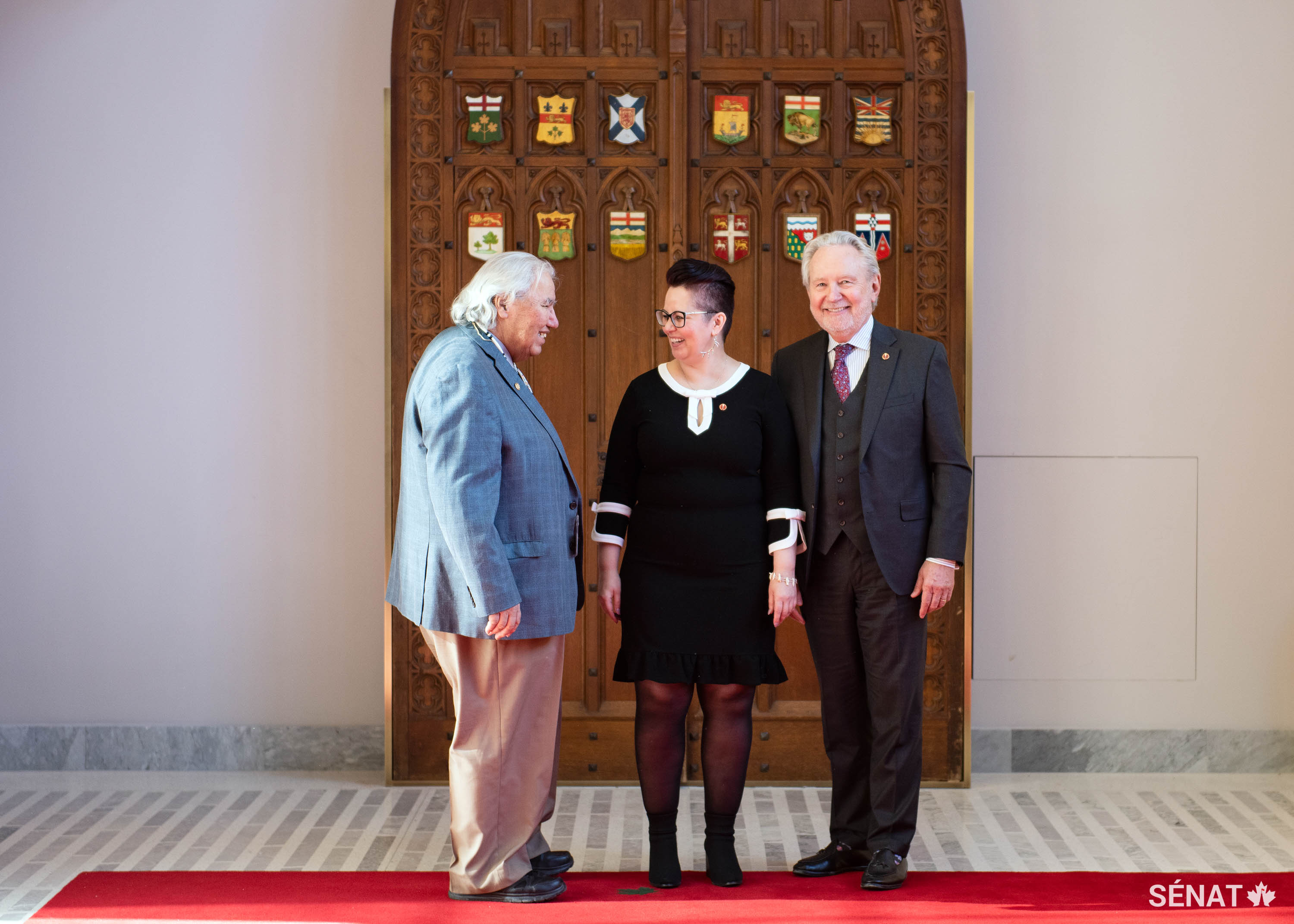 Le sénateur Murray Sinclair, à gauche, et le sénateur Peter Harder accueillent la sénatrice Margaret Dawn Anderson au Sénat après son assermentation le 19 février 2019.