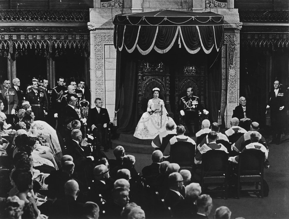 In the Senate Chamber with Prince Philip beside her, Queen Elizabeth II reads the Speech from the Throne to open Canada’s 23rd Parliament on October 14, 1957. (Library and Archives Canada)