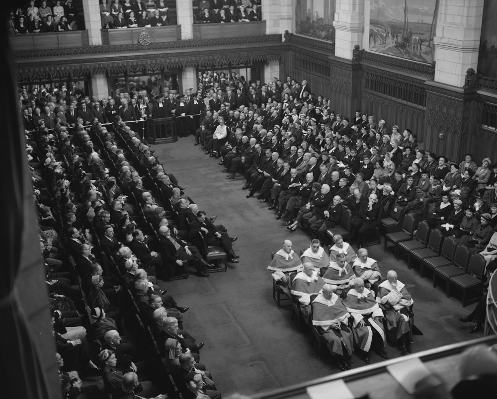 During the opening of the 22nd Parliament in 1953, an expanded roster of nine Supreme Court judges sat on hard-backed chairs. (Library and Archives Canada)
