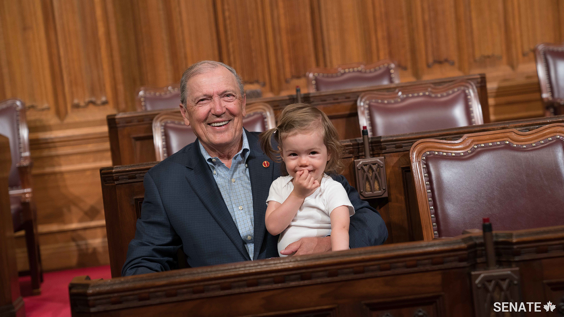 Senator Tkachuk and his granddaughter share a smile and a cuddle in the Senate Chamber in 2017. He looks forward to spending more time with his family during his retirement.