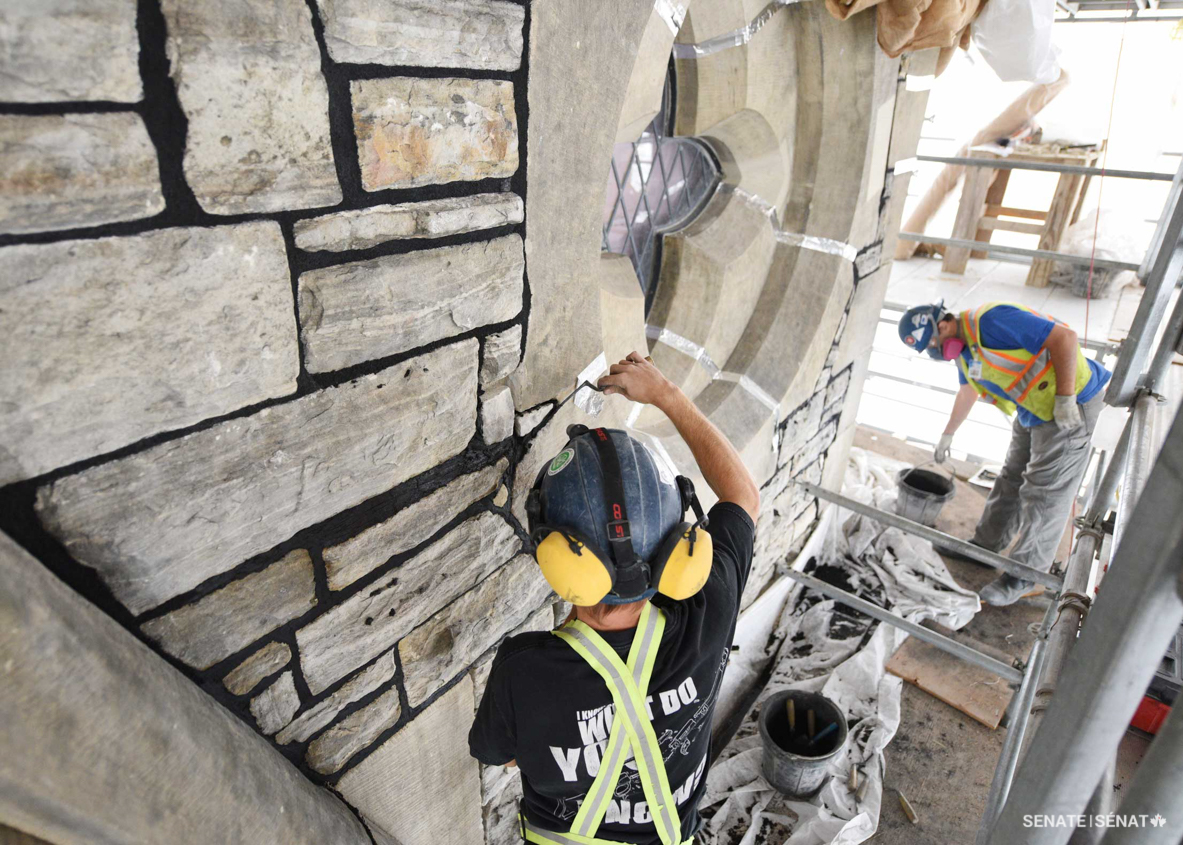 Masons working on East Block’s rehabilitation fill in the joints of laser-cleaned stonework with mortar. The final mortar mix is dyed a dark colour, which helps the lighter stones stand out. Workers followed all construction safety and public health rules in place at the time the work was performed.
