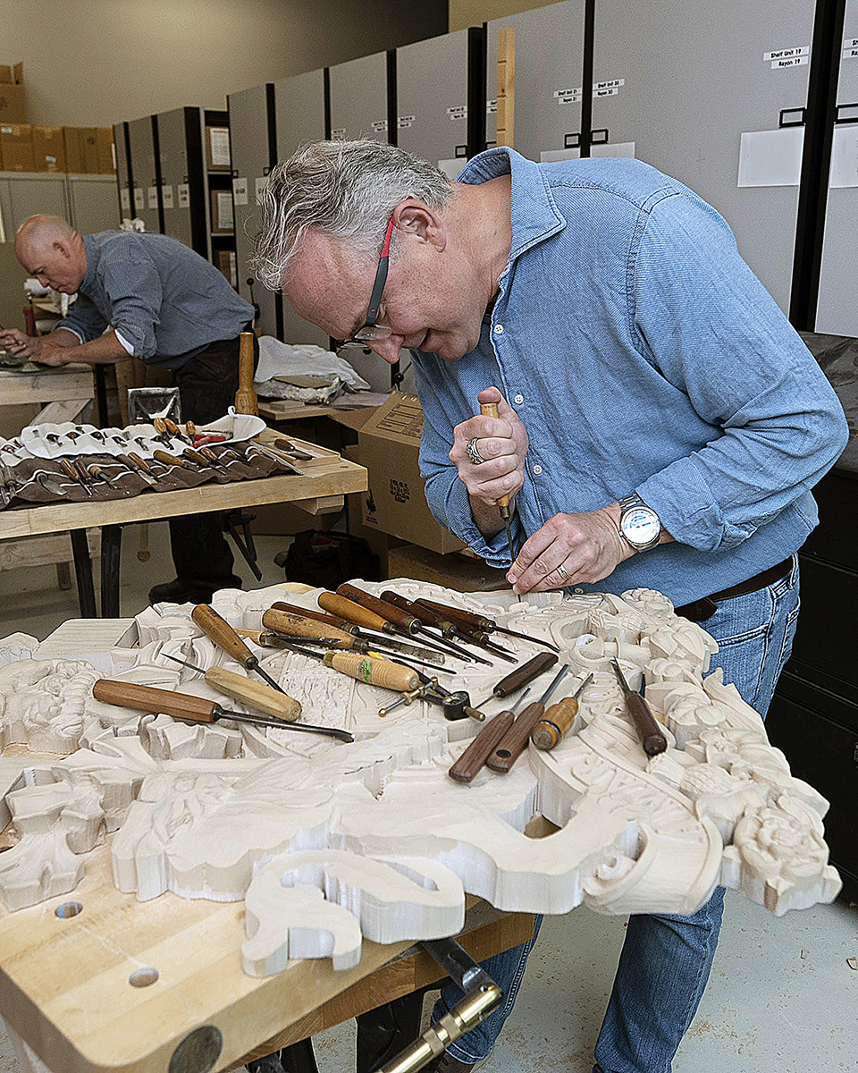 Mr. White carves a depiction of the Arms of Canada in high-density polyurethane foam board, a modern alternative to wood, in 2017. The piece, which now hangs in the temporary Senate Chamber in the Senate of Canada Building, was finished in a tissue-thin veneer of metallic leaf that makes the carving look like it was cast in metal. (Photo credit: Public Services and Procurement Canada)