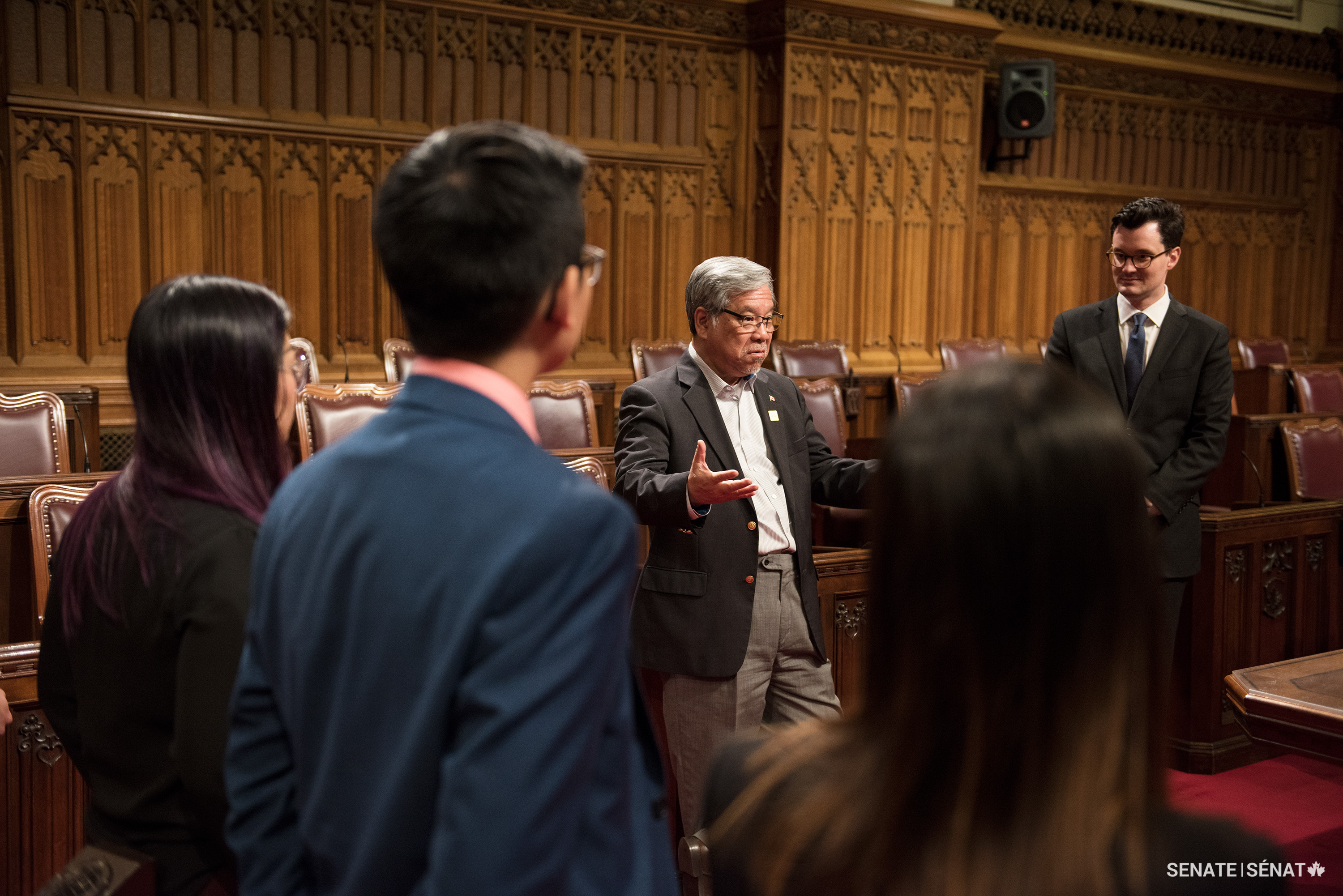 Senator Ngo, centre, explains aspects of the Senate to his interns on the floor of the Red Chamber in Centre Block — now closed for rehabilitation — in this 2017 photo. Senator Ngo offered an annual summer internship to Canadian post-secondary students from Vietnamese communities so they could learn about human rights issues and gain practical work experience.
