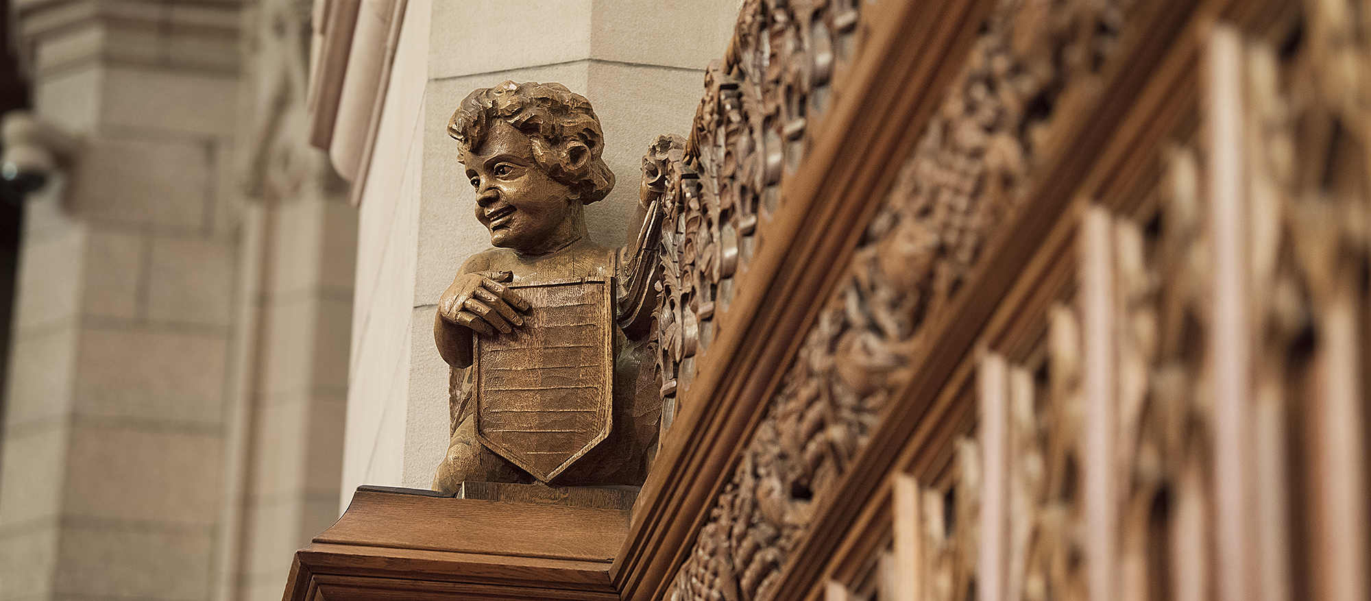 A carving of a smiling angelic child atop decorative wood panelling.